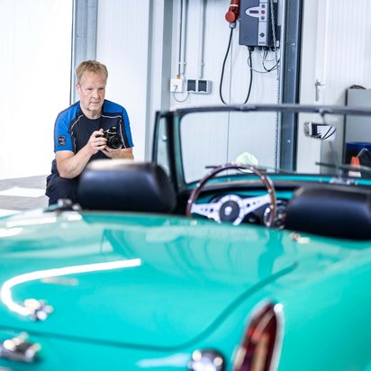 TÜV NORD Experte erstellt in einer Werkstatt ein Videogutachten für ein grünes Cabriolet zur schnellen Schadensbewertung.